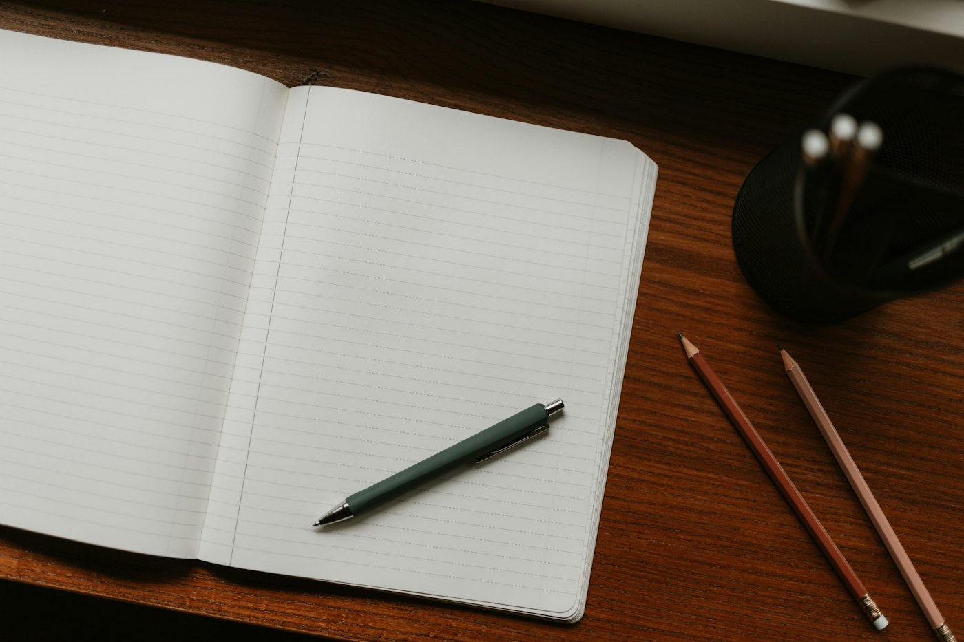 An open notebook and pen on a wooden desk, ready for a planning session