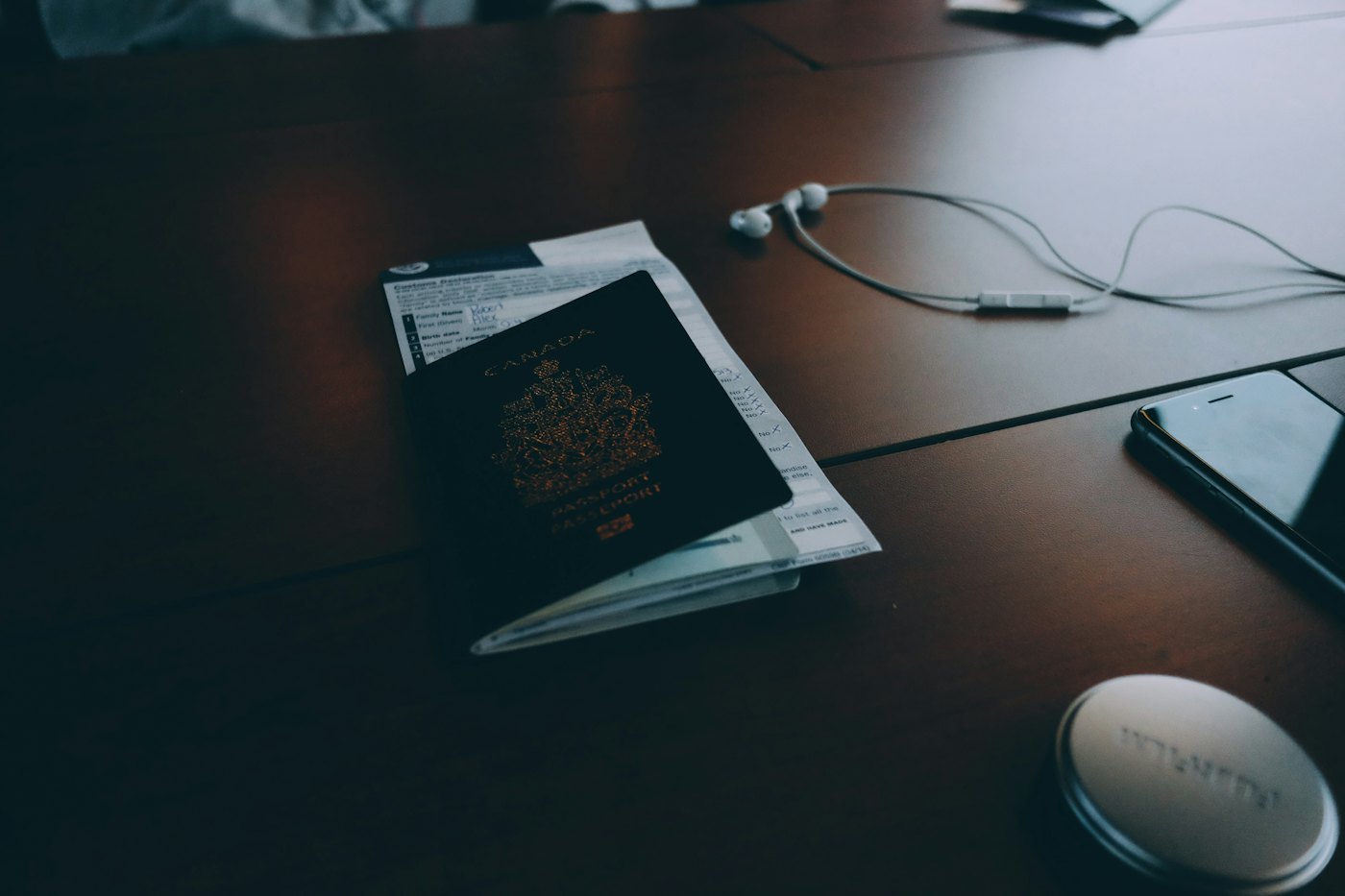 A passport and printed documents on a dark desk beside a laptop