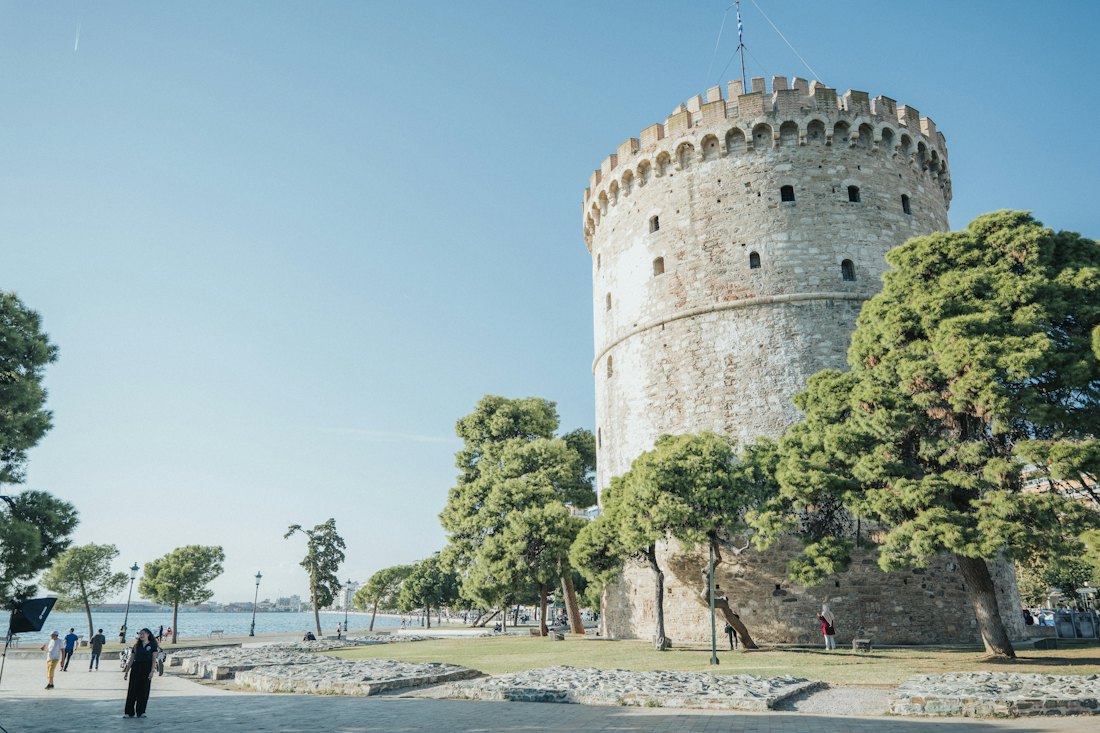 The White Tower on the Thessaloniki waterfront, with people walking along the promenade